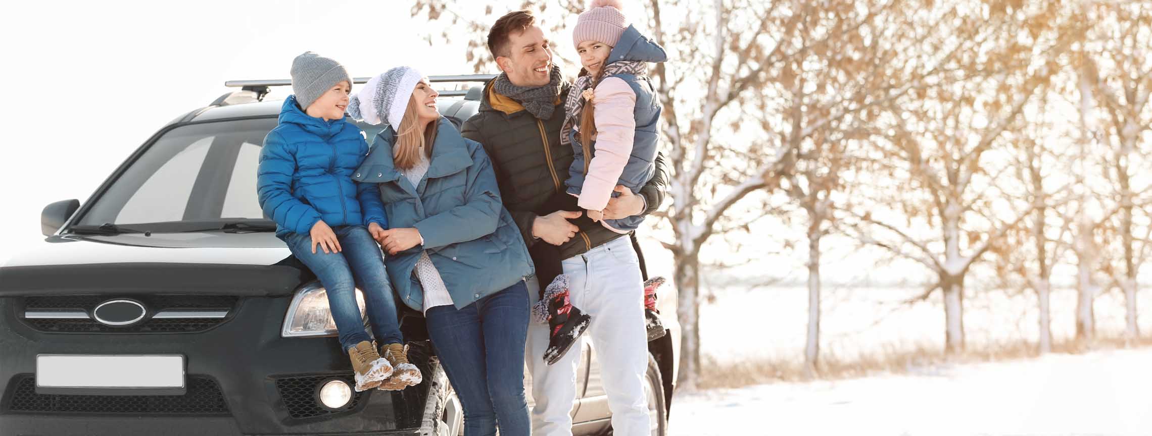Family in winter gear gathering outside of car